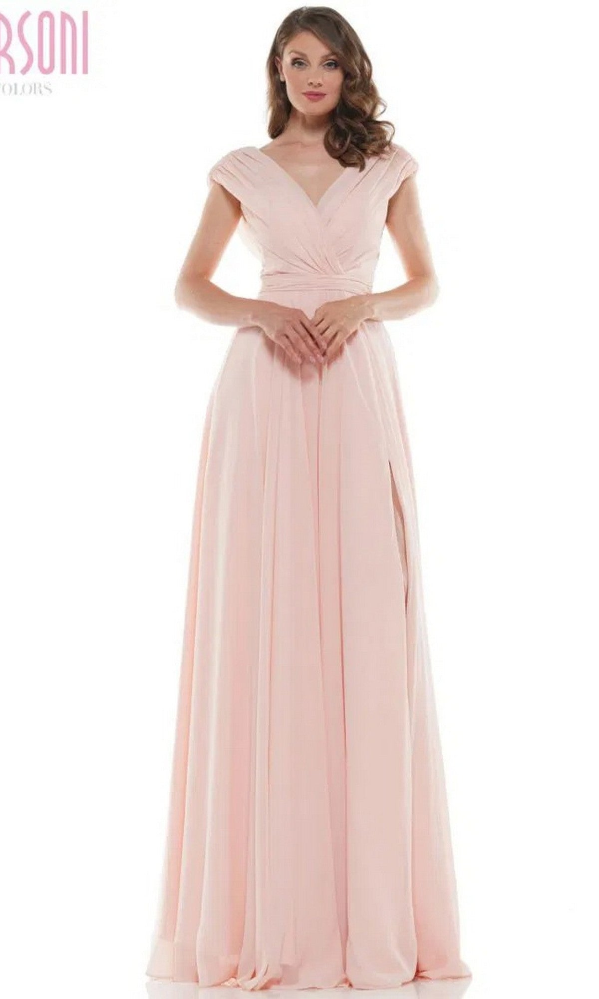 A woman models the Marsoni M251 long formal dress in blush, featuring a deep V-neckline, cap sleeves, floor-length chiffon fabric, and a high side slit, standing against a white background.